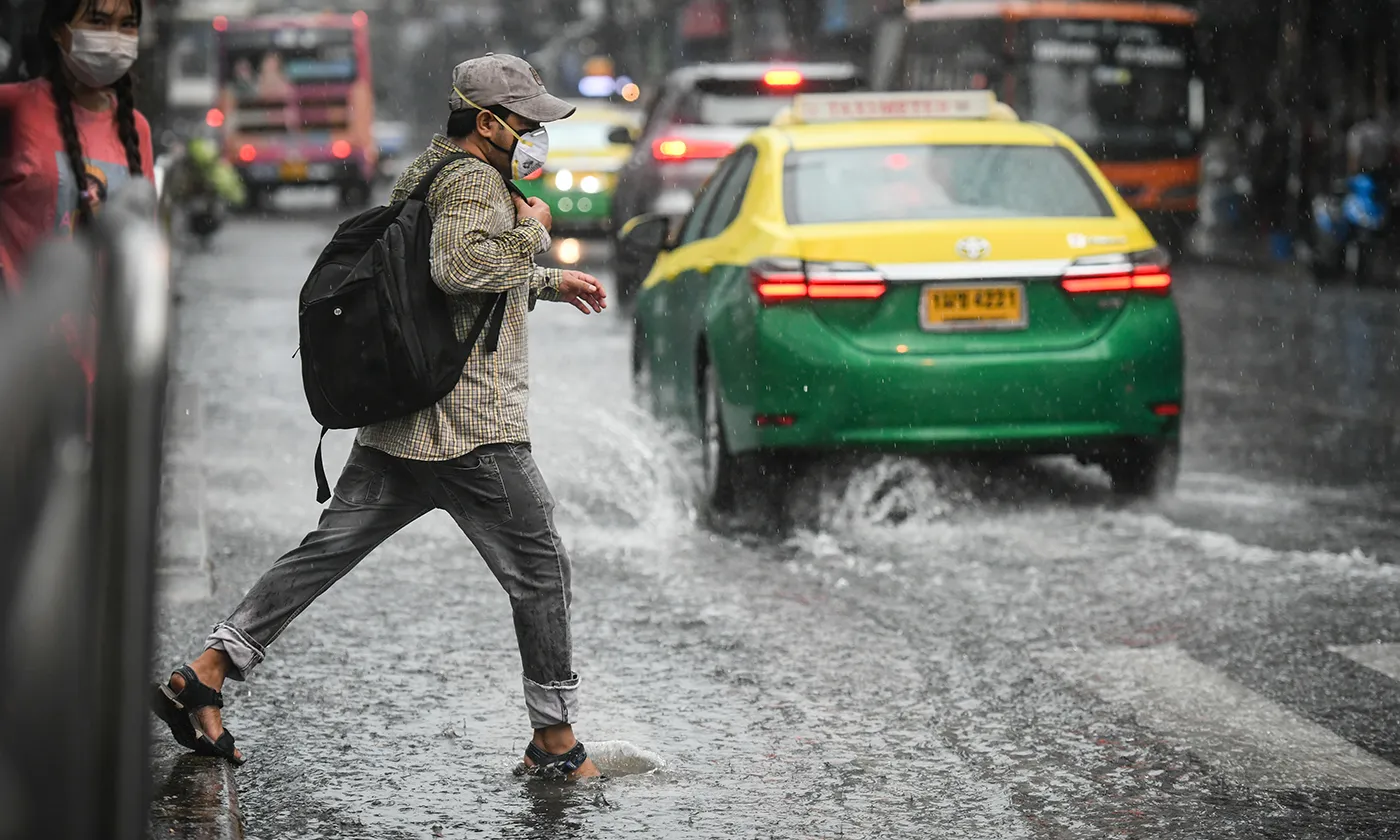A man with a backpack, crossing the street while its heavily raining
