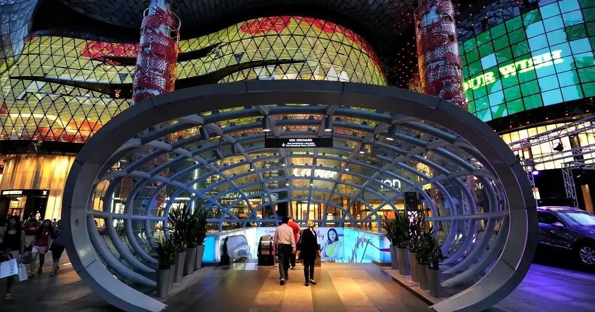 Entrada de la estación Orchard frente al centro comercial ION Orchard iluminado por la noche en Singapur.