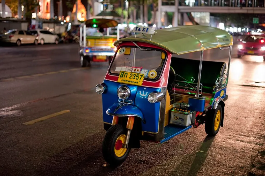 A tuktuk parked in the road at night
