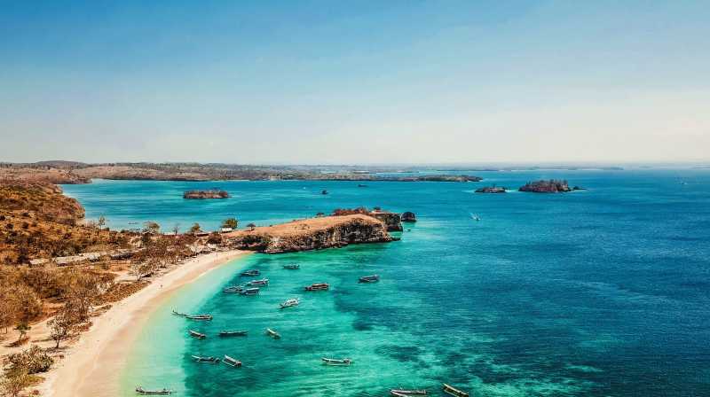 Panorámica costera de Lombok con playa de arena clara, barcas tradicionales y aguas cristalinas