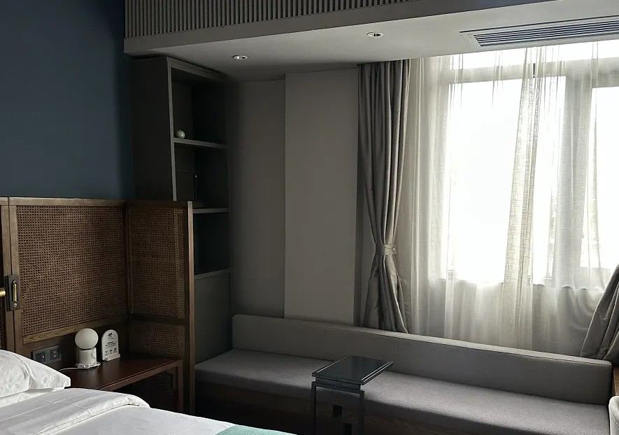 Modern hotel room with a sofa, window, and city views