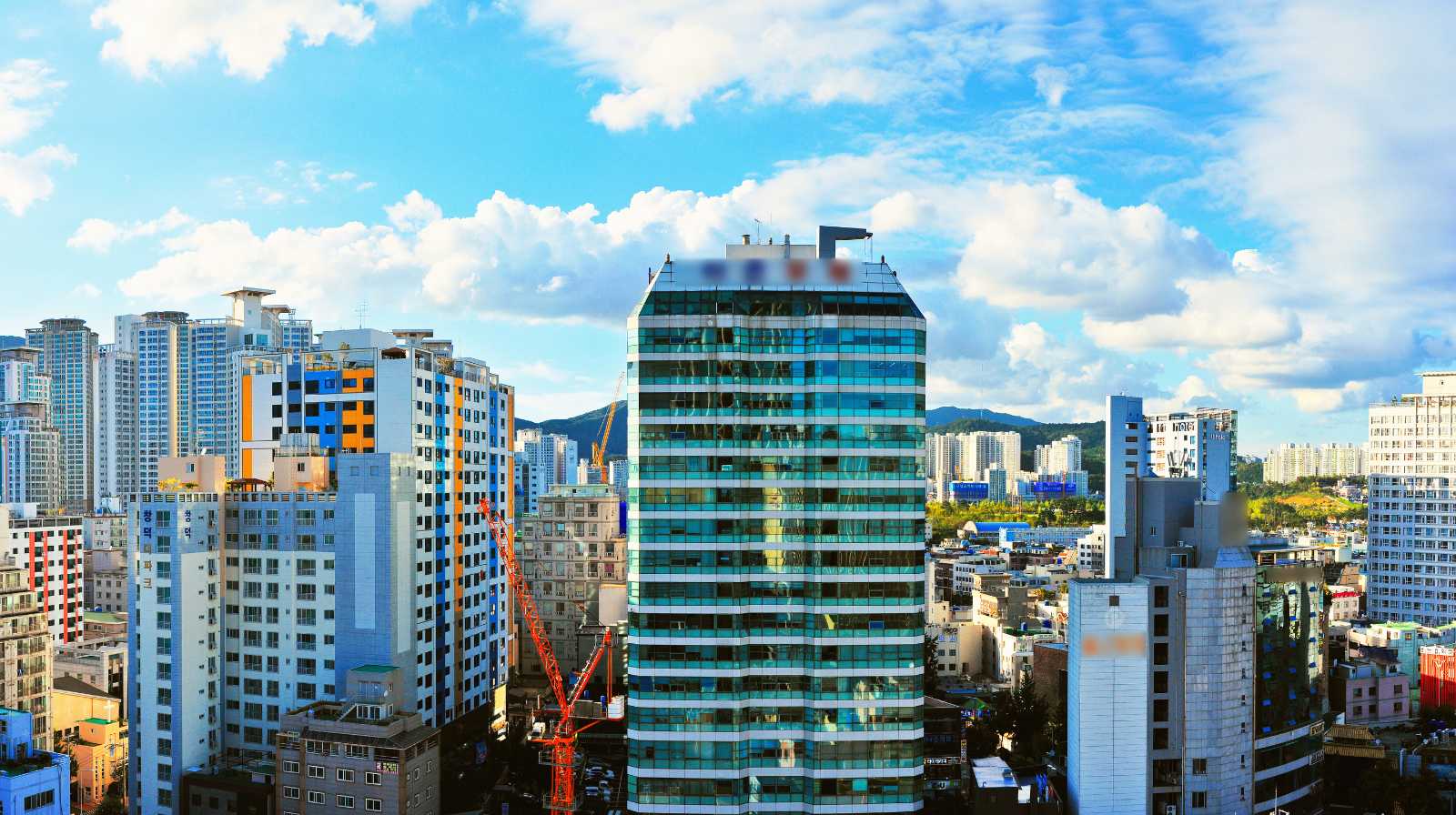 Panorámica del centro de Busan con edificios residenciales altos y una torre acristalada bajo un cielo azul