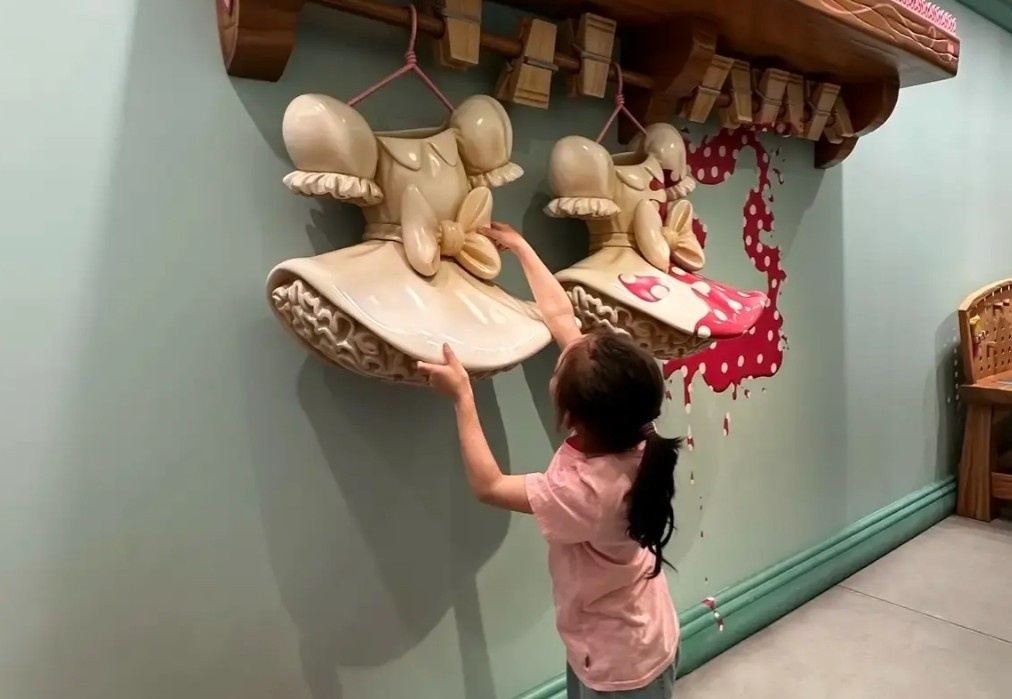 Child interacting with oversized Minnie Mouse dresses inside Tokyo Disneyland