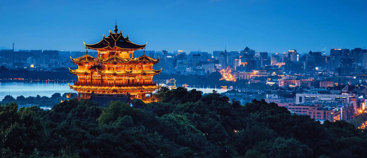 Vue nocturne d'une pagode illuminée à Hangzhou avec la skyline urbaine en toile de fond