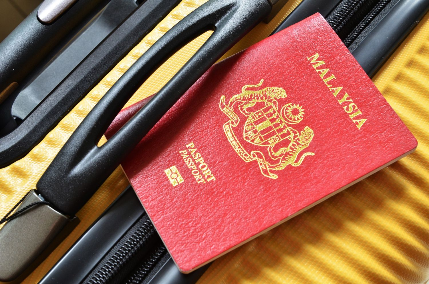 A malaysian passport next to a pair of glasses