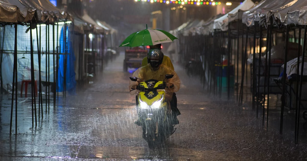 A food delivery rider braving the torrential rain and weather, going down a market road