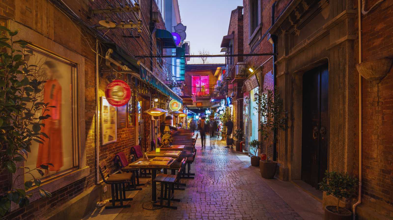 Callejón peatonal en Shanghái con bares, terrazas iluminadas y ambiente animado al anochecer