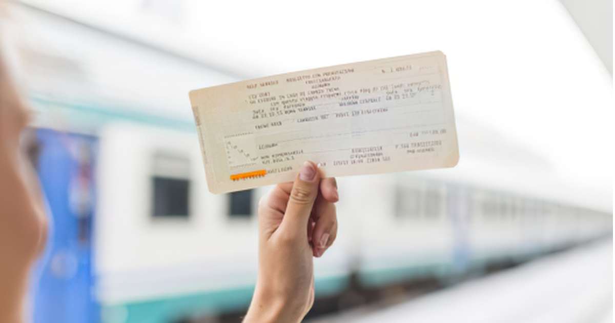 Passenger holding a printed train ticket in front of a train