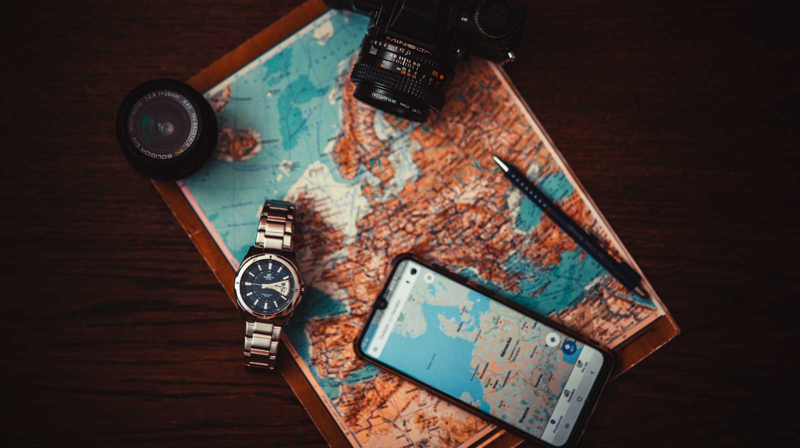 Mapa de viaje con cámara fotográfica, reloj, móvil y cuaderno, representando la planificación de un viaje por China