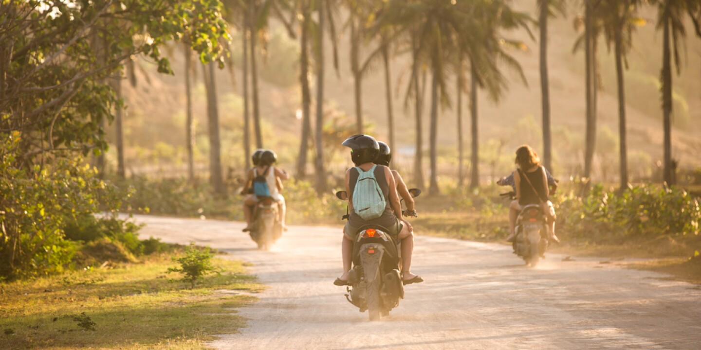 A group of tourist enjoying themselves as they ride their scooters into the sunset by the beach