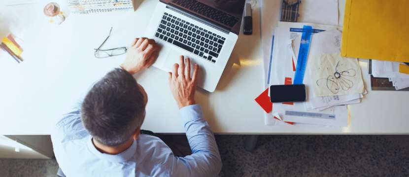 Homme travaillant sur un ordinateur portable à un bureau avec des documents et des fournitures de bureau