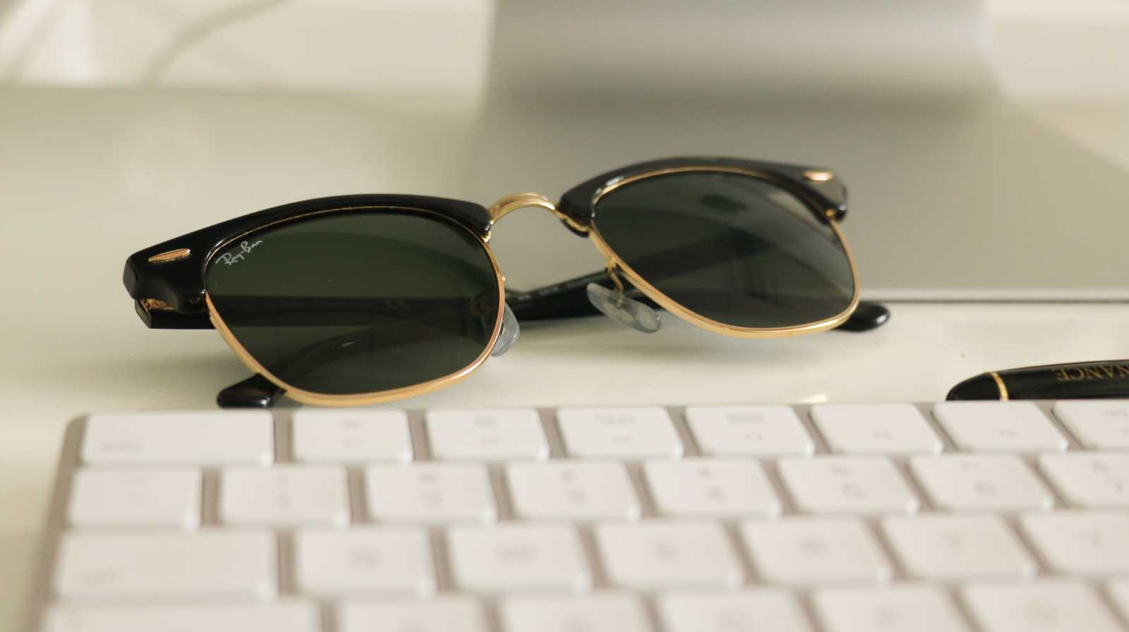 Gafas de sol de estilo clásico apoyadas sobre un teclado blanco, detalle de accesorio de moda