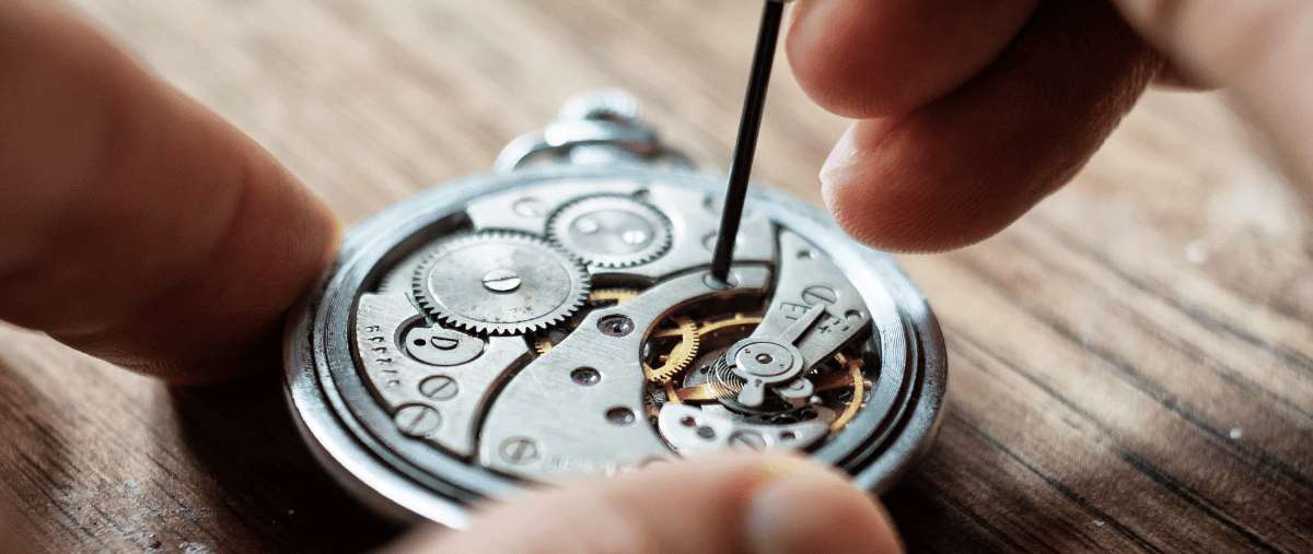 Uhrmacher, der das Innenleben einer Taschenuhr mit Präzisionswerkzeugen repariert