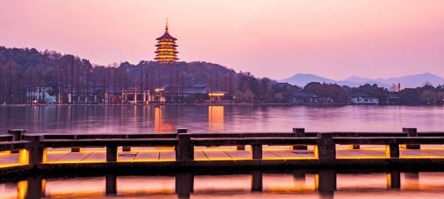 Le lac de l'Ouest de Hangzhou au coucher du soleil, avec sa pagode illuminée et ses reflets sur l'eau