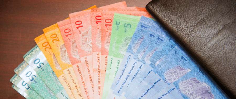 Billetes de ringgit malasio junto a cartera durante la planificación de gastos de viaje en Malasia