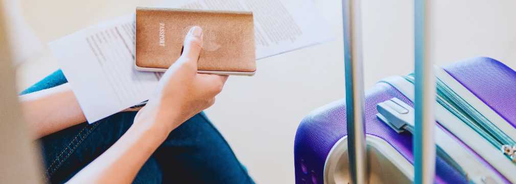 Pasaporte y tarjeta de embarque junto a maleta en aeropuerto, preparación para un vuelo internacional.