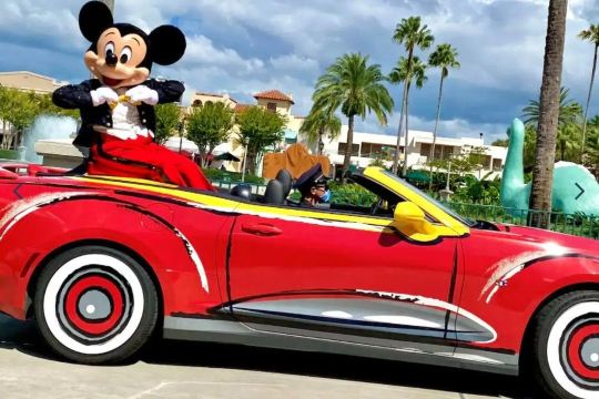 Mickey Mouse riding in a colorful car at Disney's Hollywood Studios