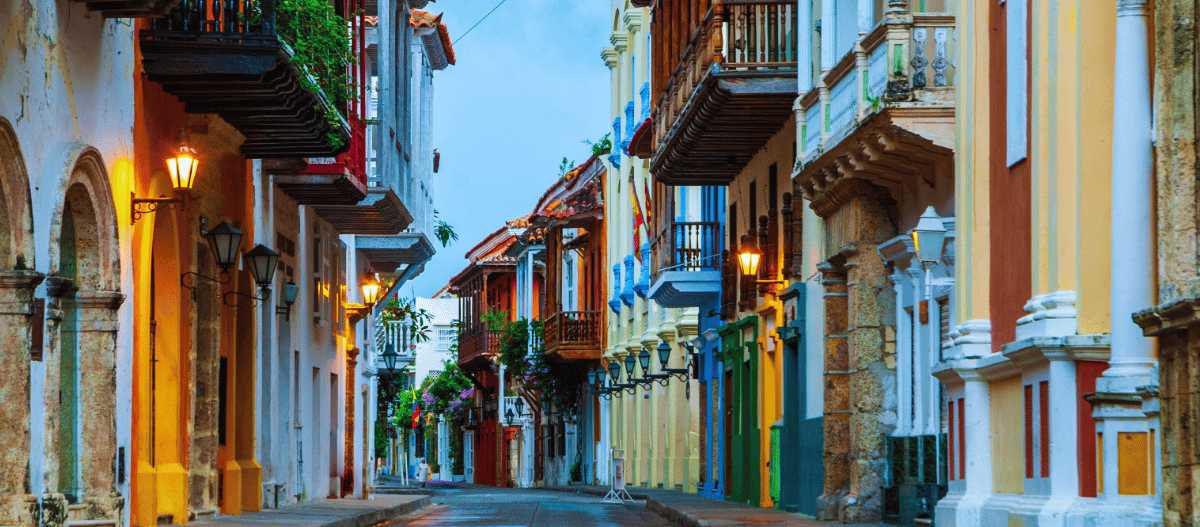 Calle colonial colorida en Cartagena de Indias con balcones de madera y faroles encendidos