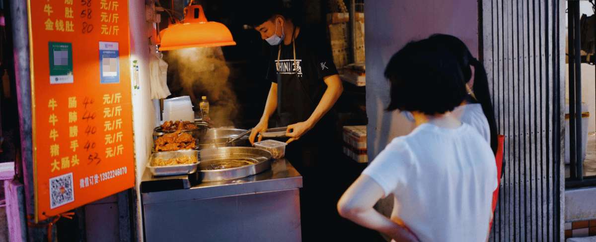 Puesto de comida callejera en Pekín con vendedor cocinando platos locales