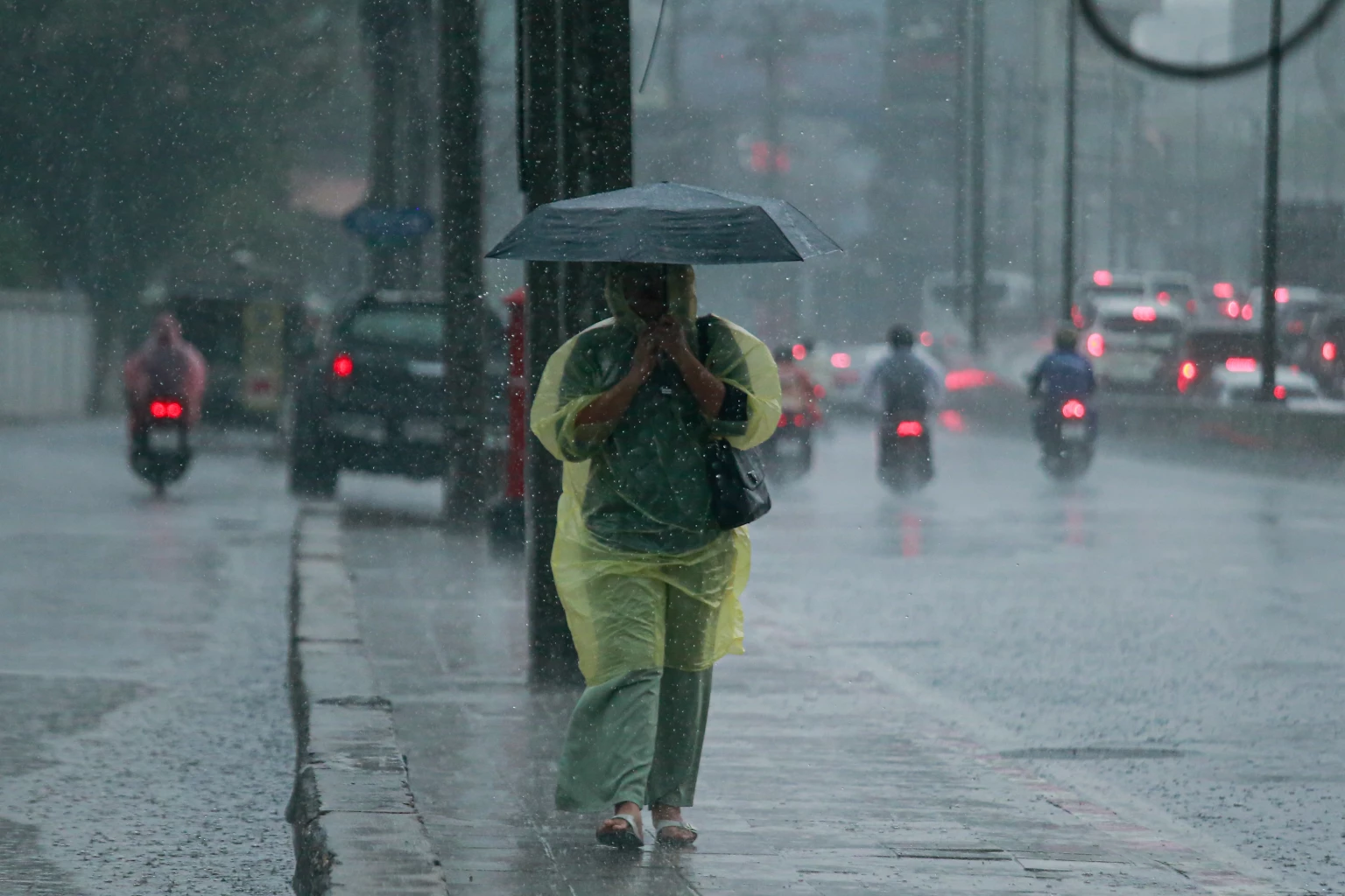Guy with raincoat and umbrella, walking under heavy rain