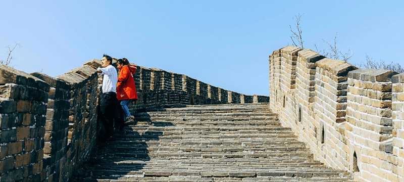 Pareja de turistas caminando por las escaleras de la Gran Muralla China en un día despejado.