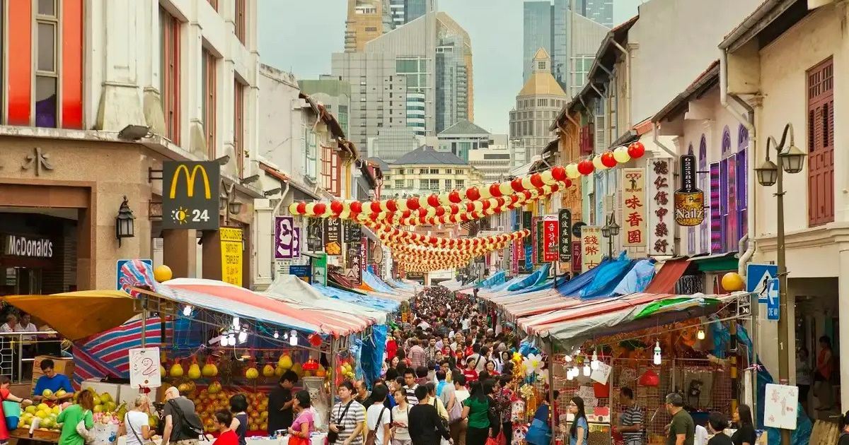 Puestos y comercios de Chinatown decorados con farolillos rojos en una concurrida calle de Singapur.
