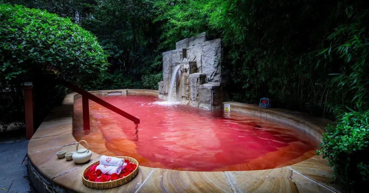 Thermal-Außenpool mit Wasserfall, umgeben von üppigem Grün, im Xi’an Lintong Angsana Hot Spring Hotel.