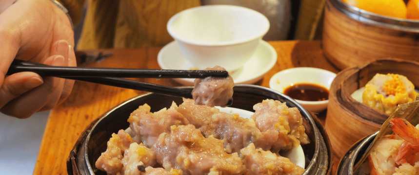 Dim sum servido en cesta de bambú con palillos, comida típica china para probar durante una escala en Shanghái