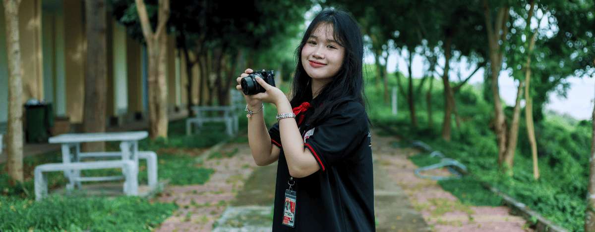 Une photographe tenant son appareil photo dans un parc urbain de Shanghai lors d'une visite touristique