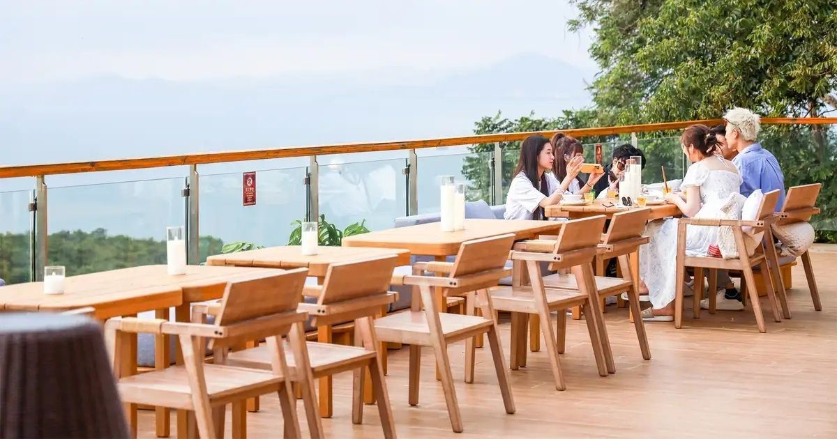 Terraza panorámica con mesas y visitantes en el Área Escénica de Luhuitou, Sanya.