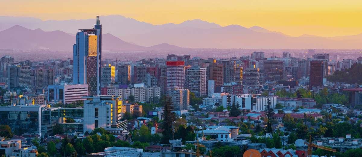 Vista panorámica de Santiago de Chile al atardecer con edificios modernos y la cordillera de fondo
