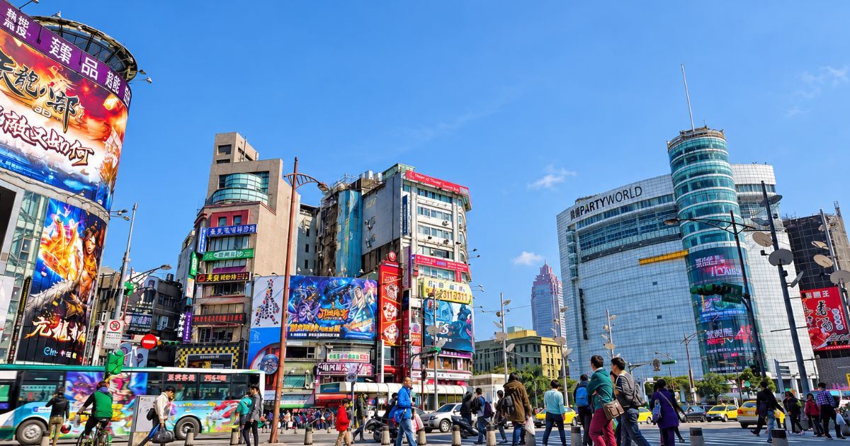 Cruce concurrido de Ximending rodeado de edificios comerciales, grandes carteles publicitarios y peatones en Taipéi