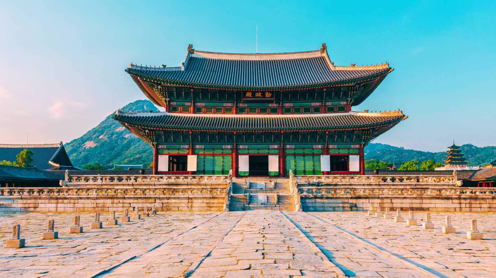 Fachada principal del palacio Gyeongbokgung en Seúl con montañas al fondo y cielo despejado