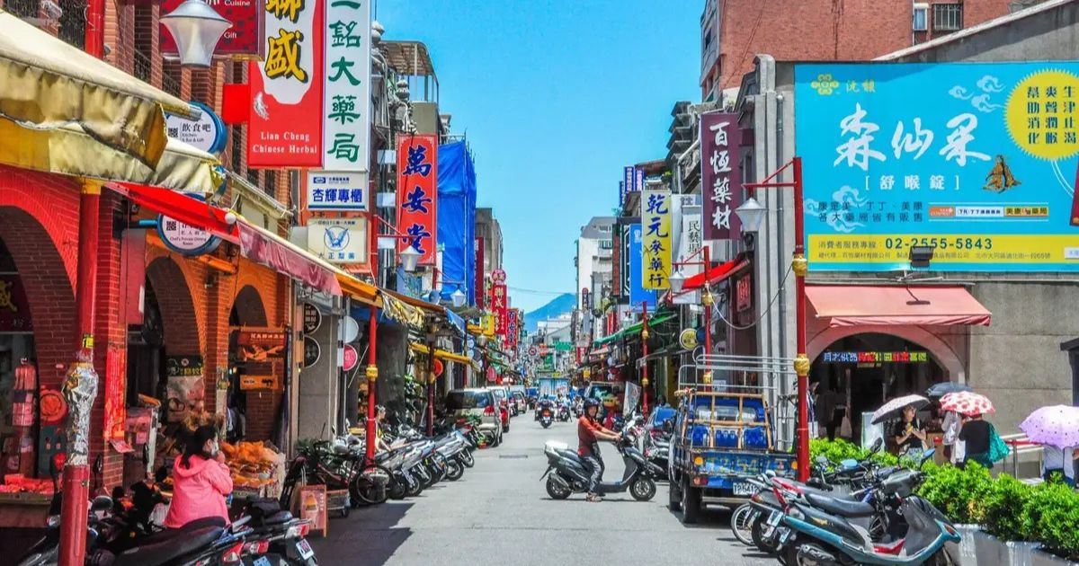 Calle comercial de Dadaocheng con tiendas tradicionales, carteles en chino y motocicletas estacionadas cerca de Dihua Street, en Taipéi