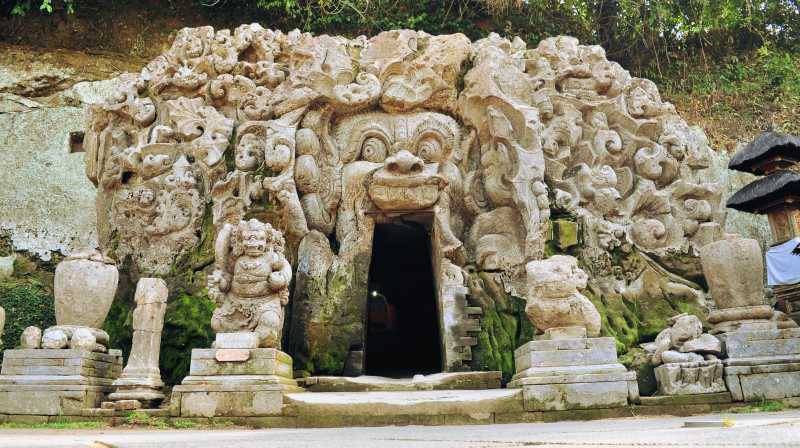 Entrada de la cueva de Goa Gajah con esculturas de piedra cubiertas de musgo en Ubud