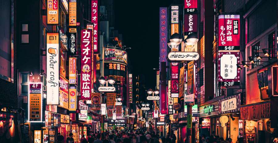 Calle comercial iluminada en Tokio con tiendas y restaurantes abiertos por la noche