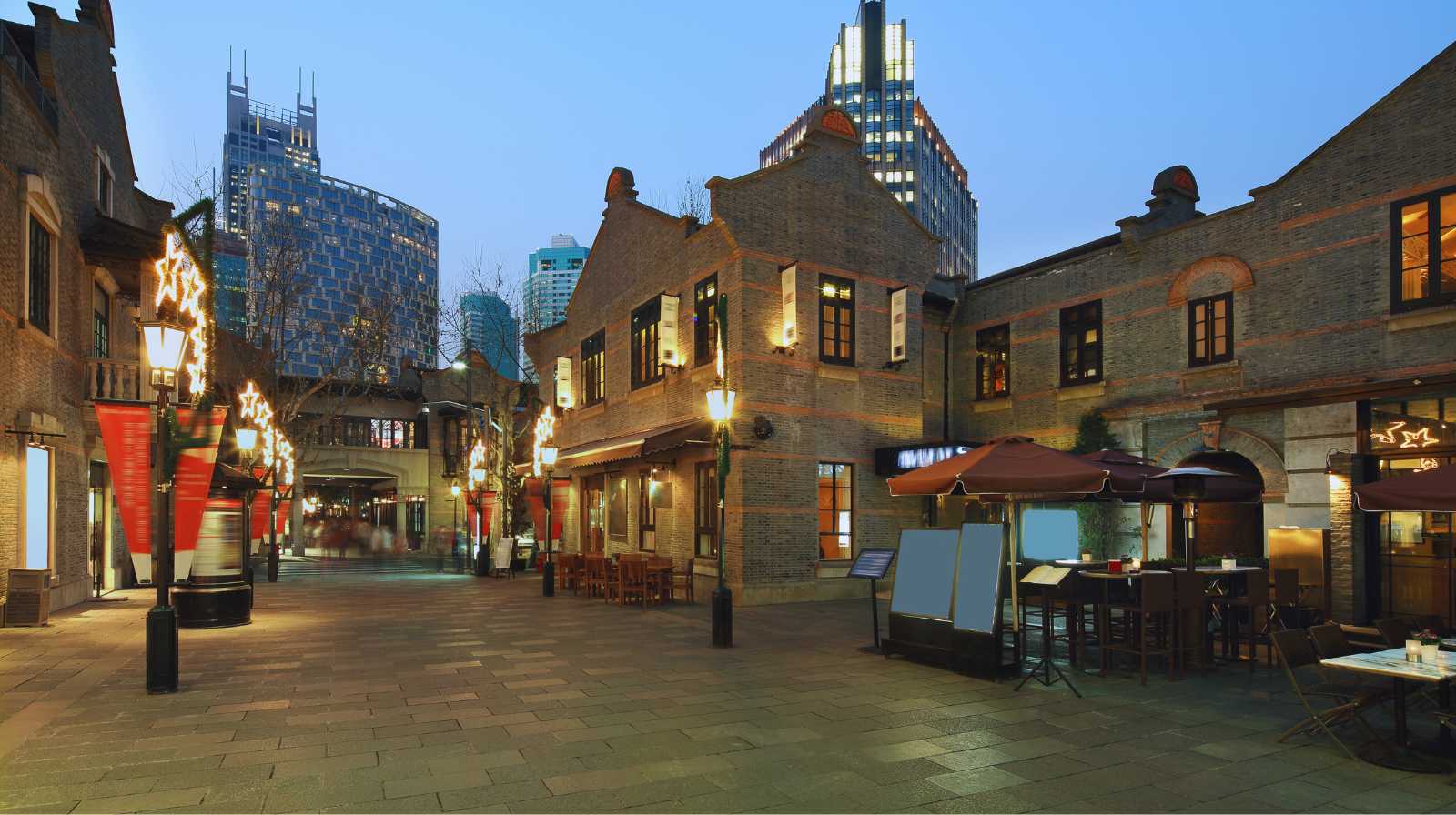Zona histórica de Shanghái con edificios de ladrillo, restaurantes y luces decorativas al atardecer
