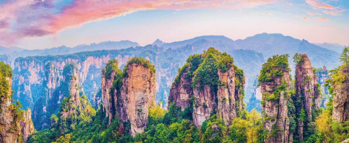 Montañas de Zhangjiajie al amanecer con formaciones rocosas cubiertas de vegetación.