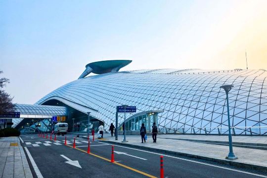 Exterior of a modern airport terminal with curved architecture and glass walls.
