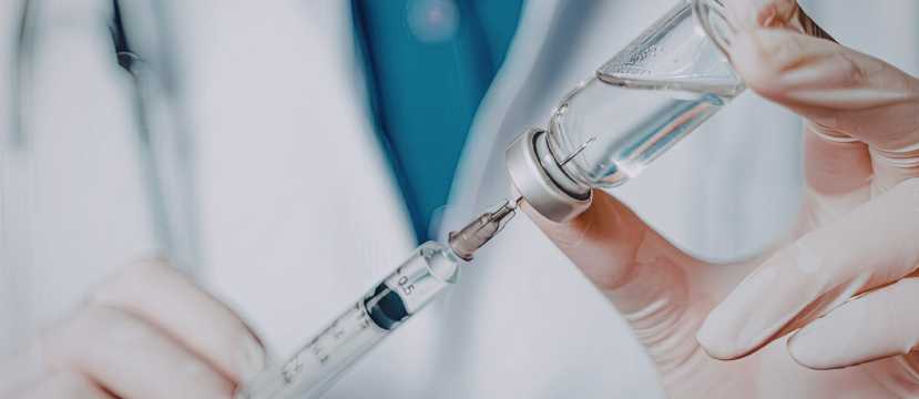 Profesional de salud preparando vacuna con jeringa y vial, requisito sanitario para viajar.