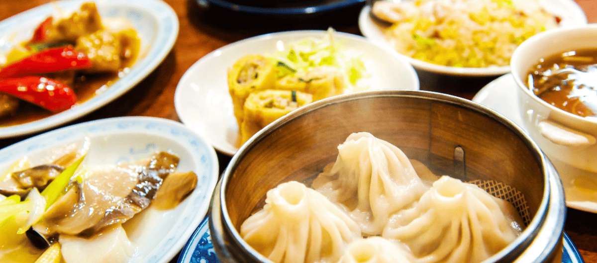 Shanghainese xiaolongbao in a bamboo steamer served with fried rice and dim sum