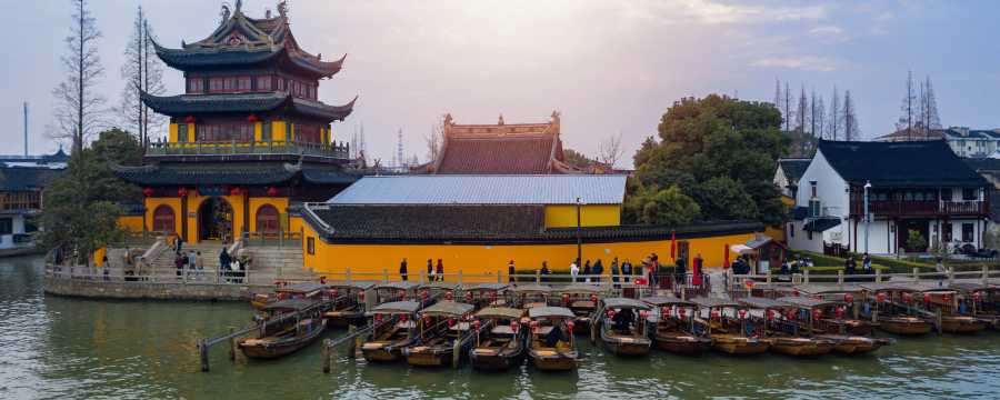 Templo tradicional chino junto a un canal con barcas en Shanghái, arquitectura histórica y turismo cultural en la ciudad