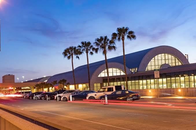 John Wayne Airport exterior with palm trees and evening traffic