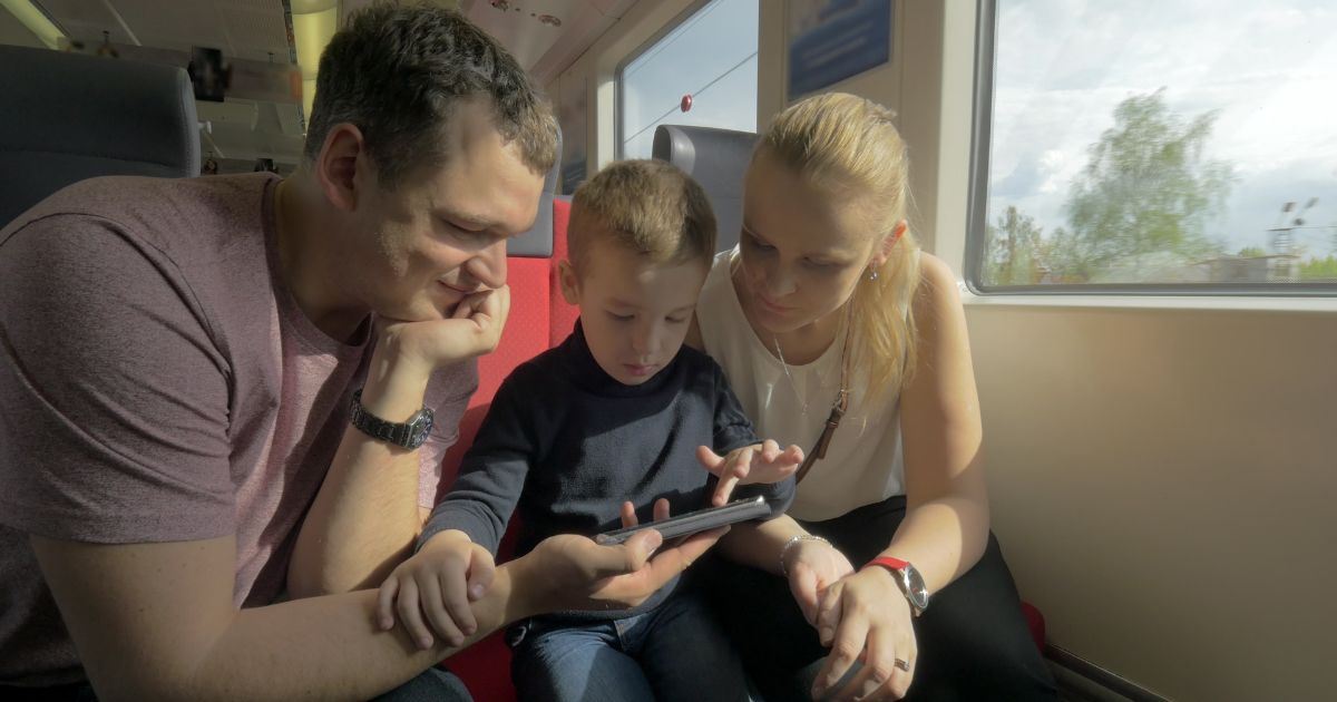 Family using a smartphone together while traveling by train