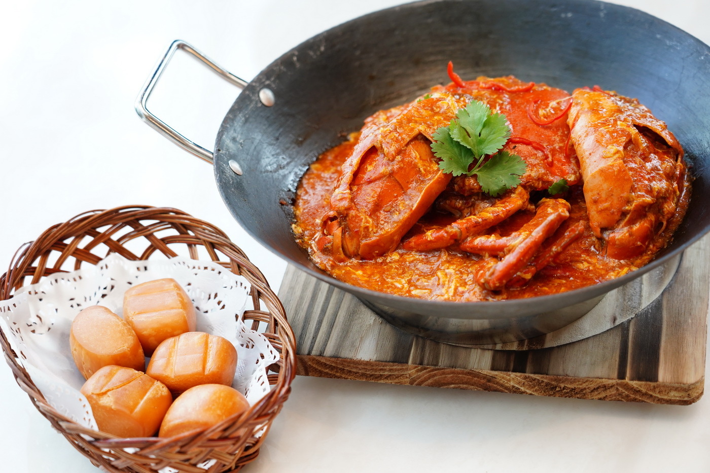 A delicious and spicy looking chili crab dish with a side of mantous