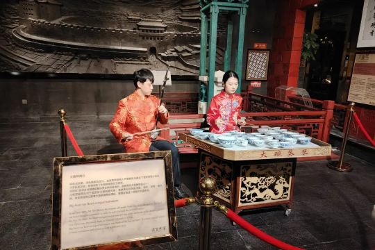 Tea ceremony demonstration with musicians and a tea server