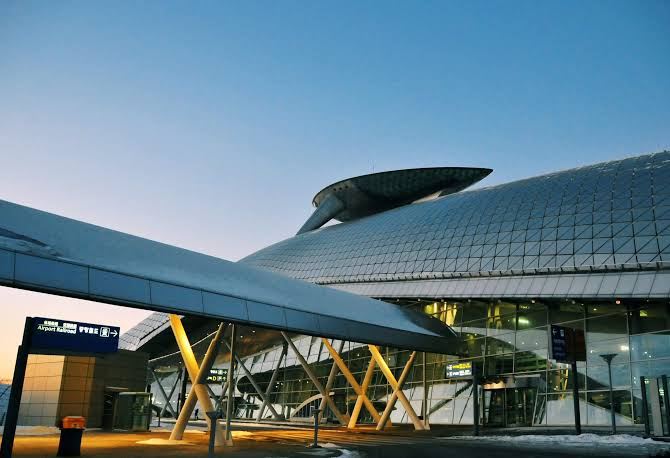 Modern airport architecture with elevated walkways and a curved glass structure at Incheon International Airport.