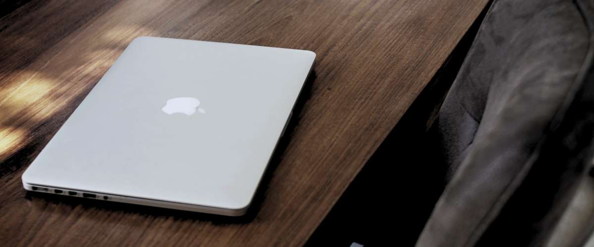 Ordinateur portable argenté avec le logo Apple fermé sur un bureau en bois