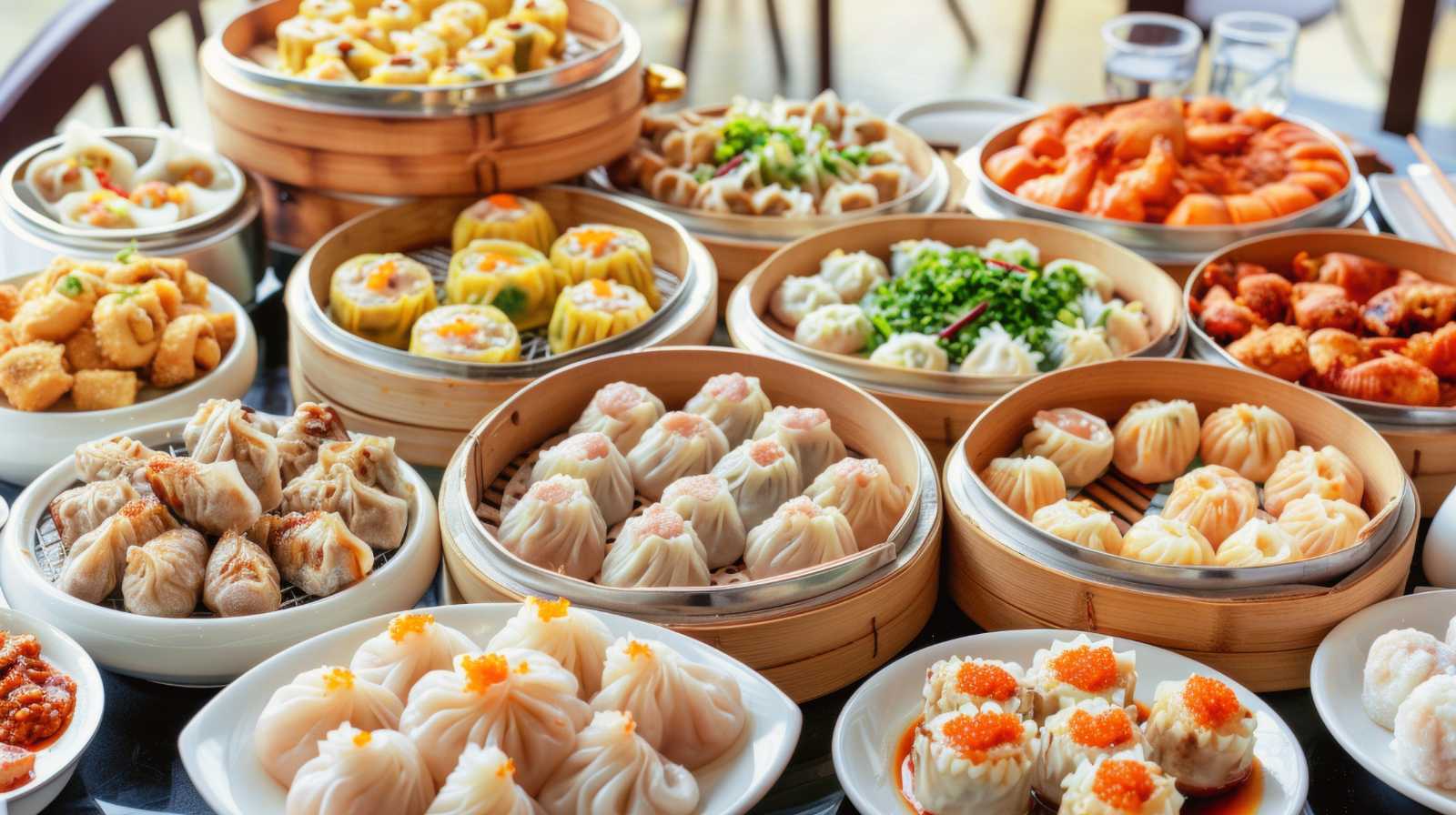 A table laden with traditional dim sum, with a variety of dumplings, siu mai and appetisers in bamboo steamers.