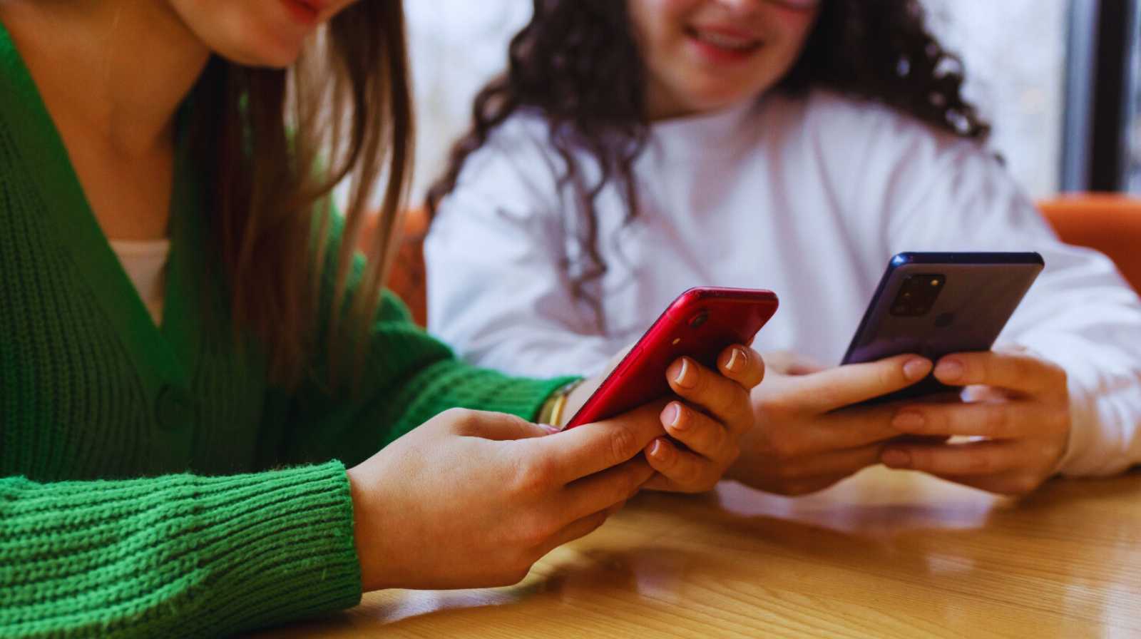 Groupe de personnes utilisant des smartphones autour d'une table, illustrant l'utilisation d'applications mobiles comme WeChat